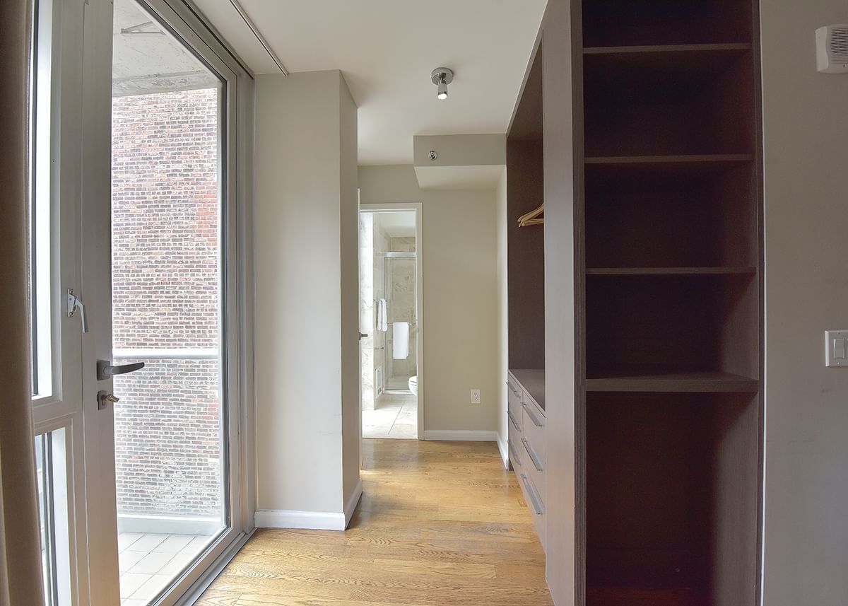 a room with a large window, shelves, and a door leading to a bathroom