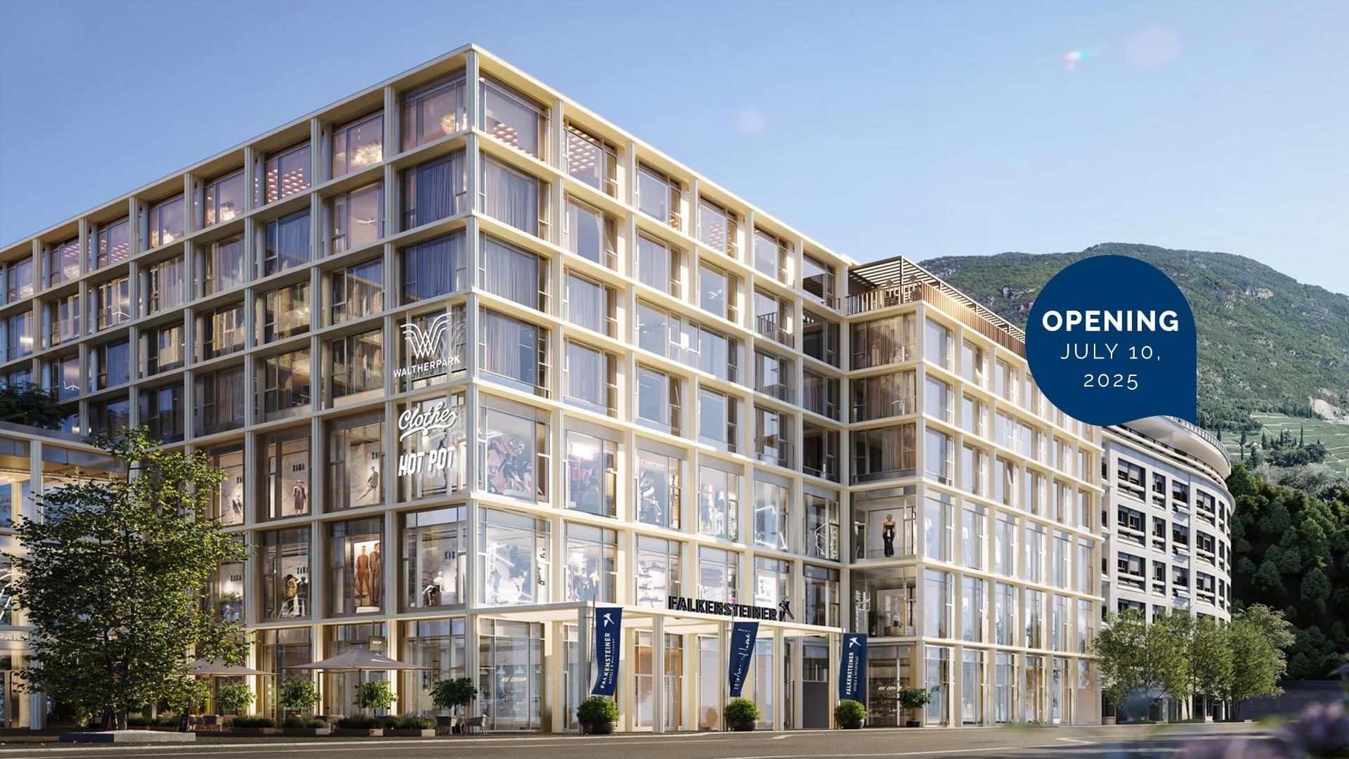Moderner Gebäudekomplex mit Glasfassaden, Eröffnungsdatum 10. Juli 2025, umgeben von Bäumen und einem Berg im Hintergrund.