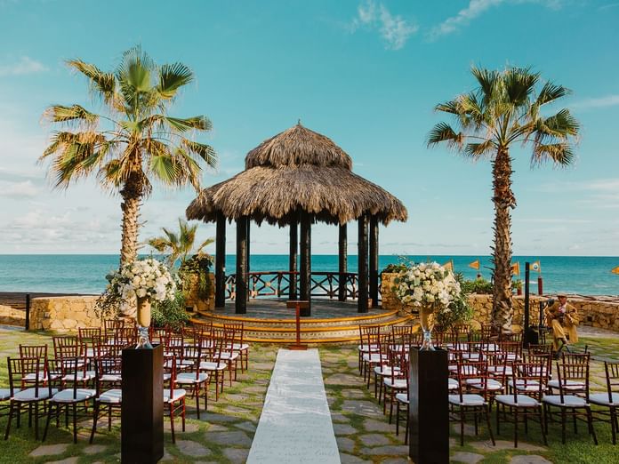 A scenic beach wedding setup at Hacienda del Mar Los Cabos with a palapa, tables, and ocean view