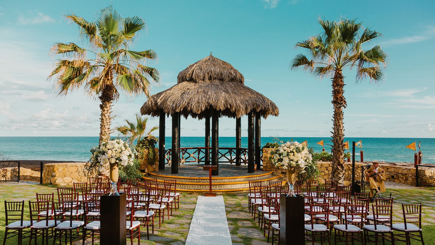 A scenic beach wedding setup at Hacienda del Mar Los Cabos with a palapa, tables, and ocean view
