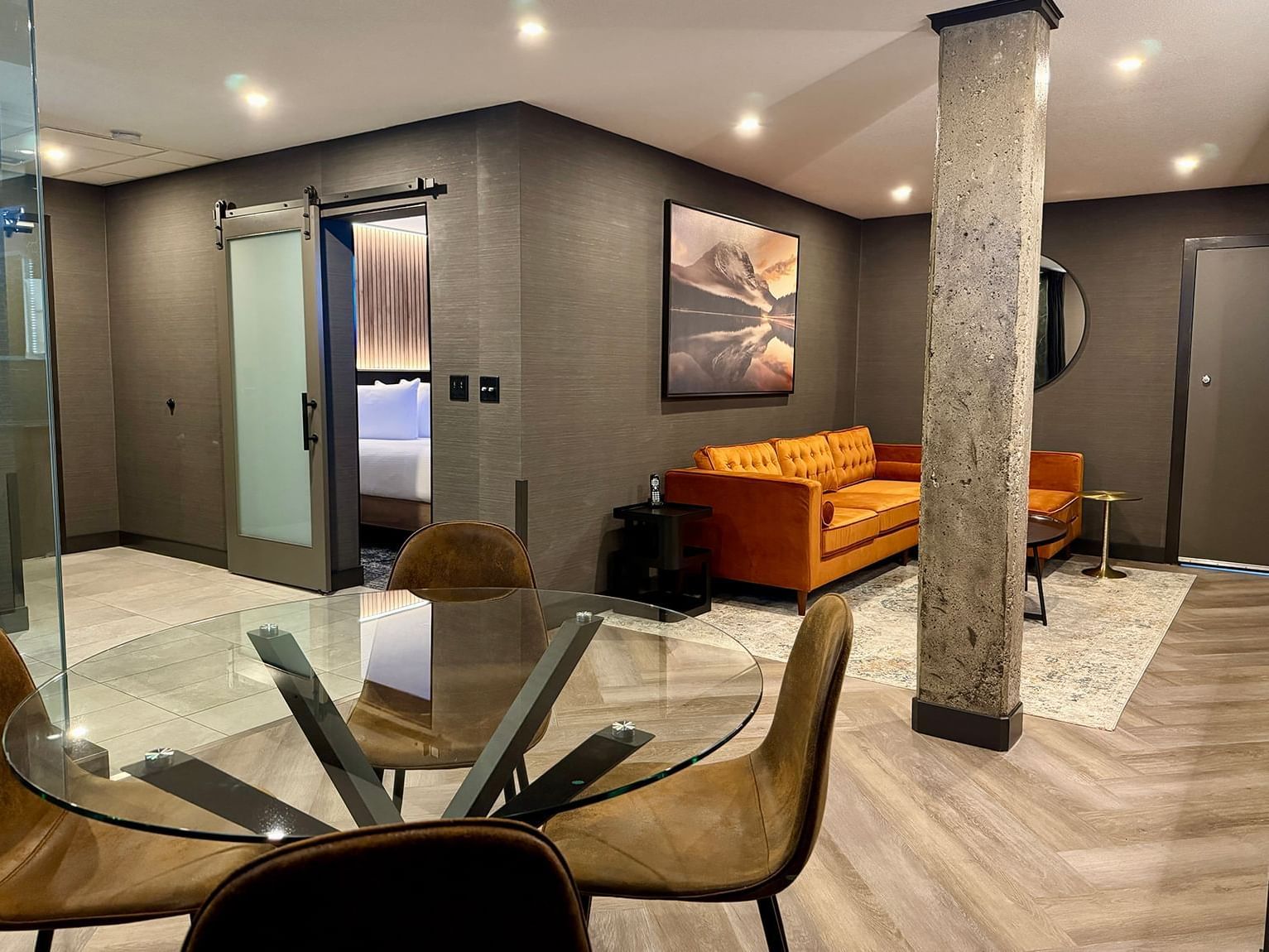 Executive Suite with a glass dining table and an orange couch at Carriage House Hotel & Conference Centre, Calgary.