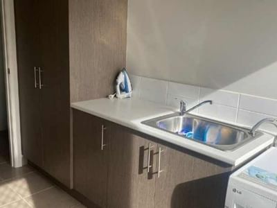 Clean laundry room with washing machine, sink, and ironing board at La Trobe University Regional Housing – Mildura.