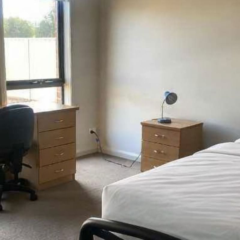 Simple room with single bed, desk, chair, and nightstand at La Trobe University Regional Housing – Mildura.