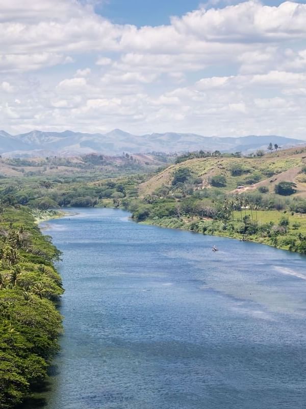 Sigatoka river safari with Wide blue river surrounding by green hills and tropical trees near Tambua Sands Beach Resort