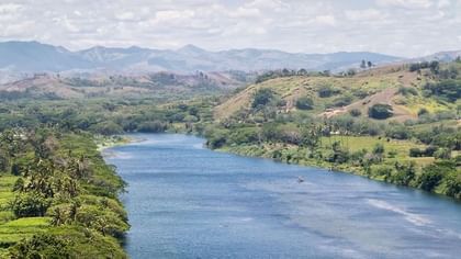 Sigatoka river safari with Wide blue river surrounding by green hills and tropical trees near Tambua Sands Beach Resort