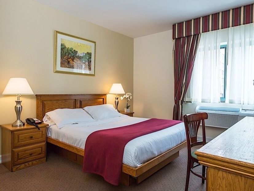 Queen bed, nightstands, window, desk, chair, and art in New York's Chelsea Savoy Hotel.