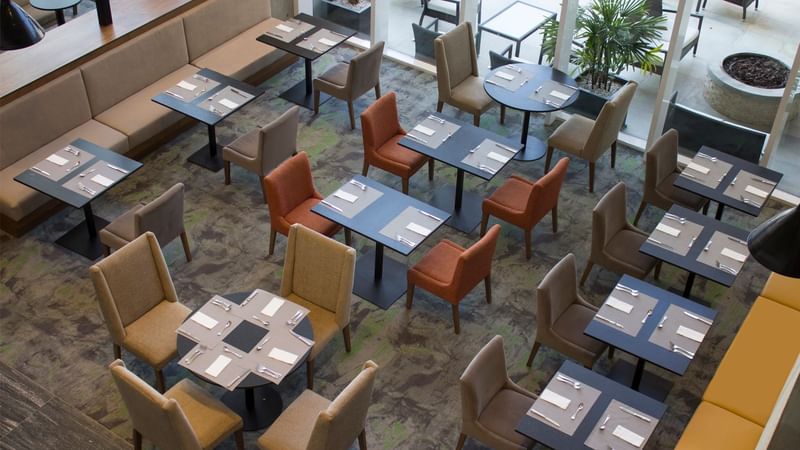 Overhead view of a restaurant with arranged tables and chairs at Fiesta Inn Suites Aeropuerto del Bajío