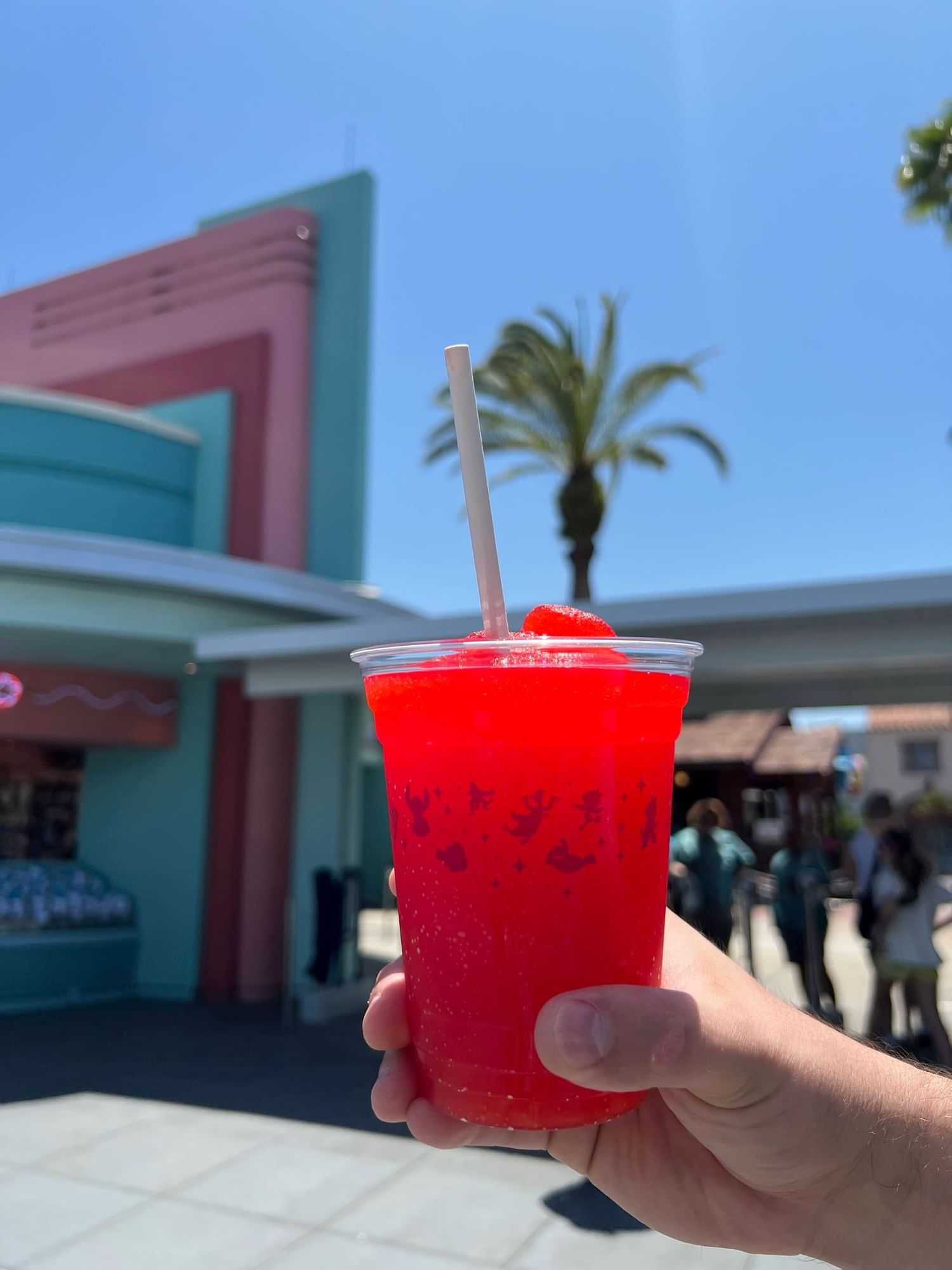 A zoomed in image of  a man's hand holding up a red, slushy drink at Disney's Hollywood Studios. Ordering food in advance means you can enjoy a cool drink without the crazy crowds. 