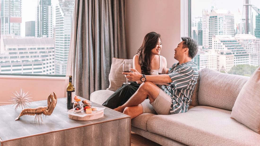 Couple enjoying wine together on a cozy sofa at Pullman Sydney Hyde Park