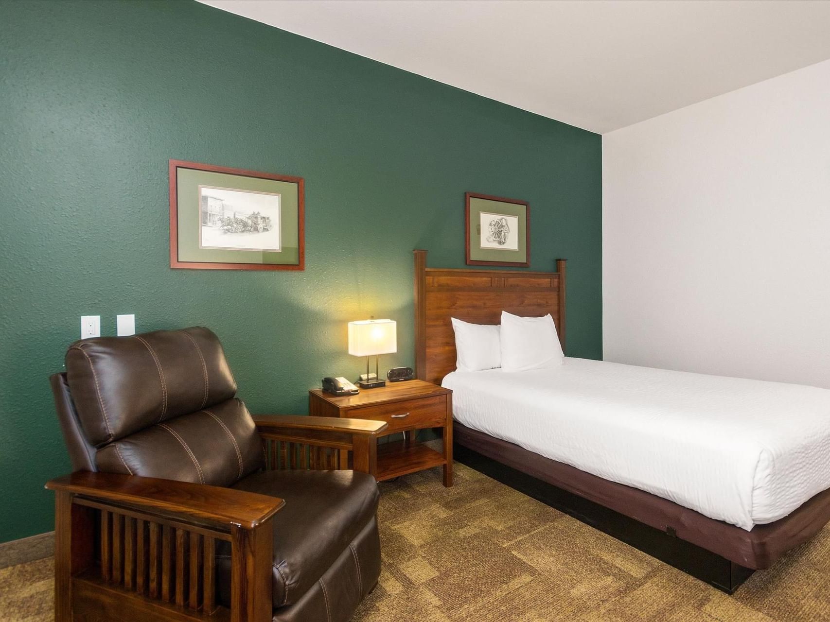 King bed, nightstand & cozy chair in Executive King at Boothill Inn & Suites