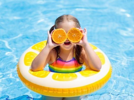 A kid in a swim ring posing with lemon pieces at Pullman Cairns