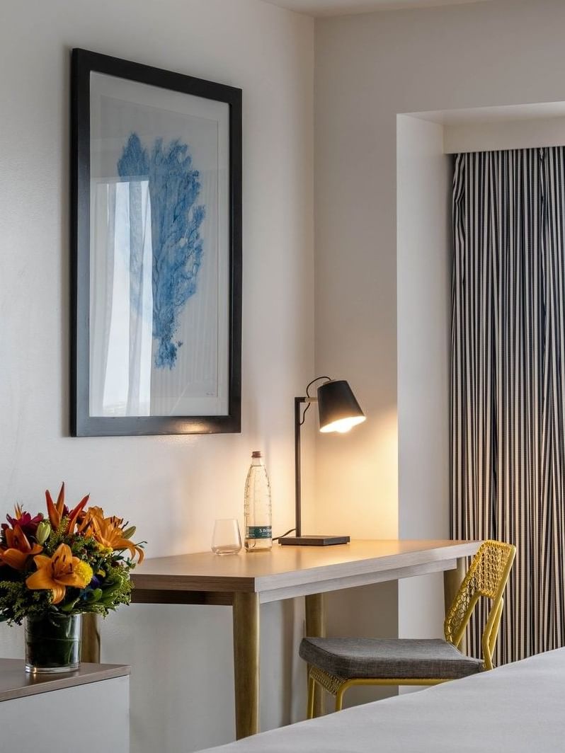 Wooden desk by a yellow chair and bright window under a framed in Harbour Deluxe Balcony at Warwick Paradise Island Bahamas