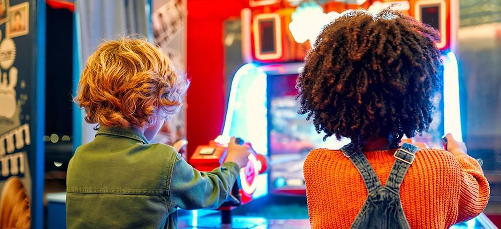 two kids playing an arcade game