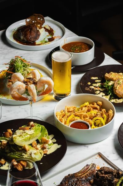 Shrimp cocktail, calamari, salad, & a beer elegantly arranged on a marble table at Cypress & Oak steakhouse in Frankfort, KY