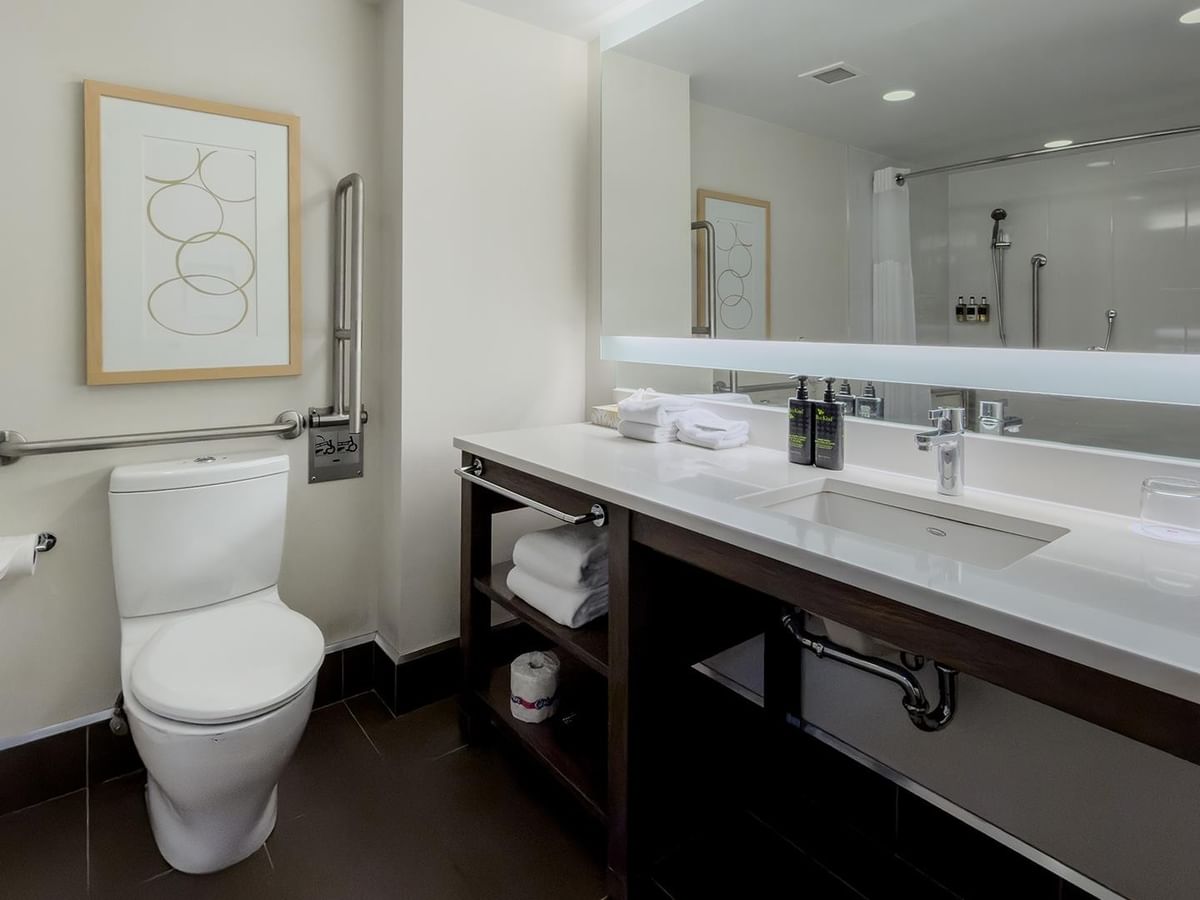 Modern accessible bathroom with toilet, sink, and mirror at Coast Bastion Hotel in Nanaimo.