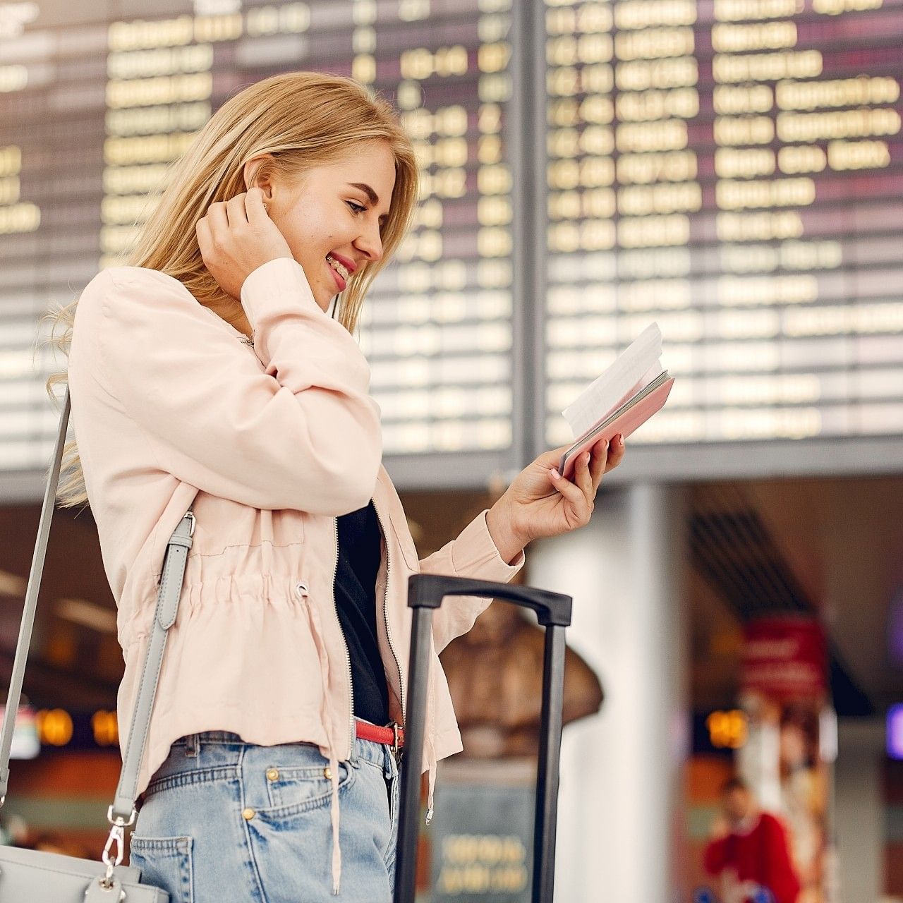 Blonde woman at an airport with a suitcase reading a book titled Pack for an Authentic Mexican Escape.