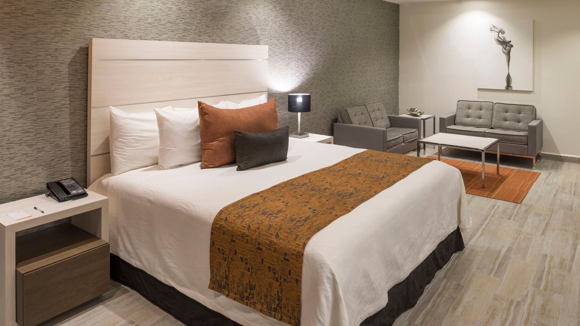 King Junior Suite with a king bed, textured grey wallpaper, and a cozy seating area at Real Inn Celaya