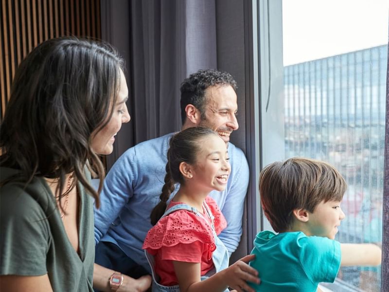 Family gazes at the city skyline through a window at Fiesta Americana