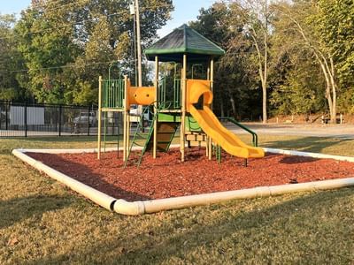 Small playground with a green and orange play structure at Fall Creek Marina & Campground