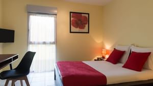 Bed with white & red bedding in a room at Originals Hotels