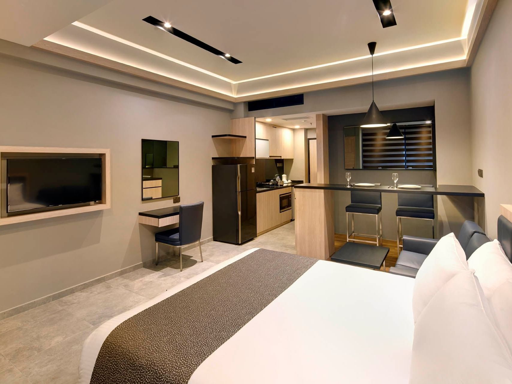 Image 10: Stylish Studio Queen at Orchard Grand Court with queen bed, kitchenette, bar seating, sleek decor, soft lighting, and a TV