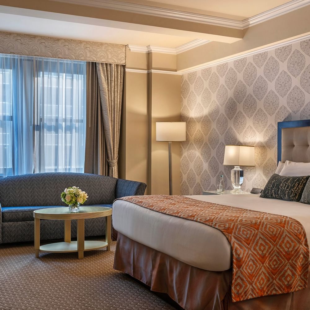 Bed with sofa near the window in the Junior Suite at Warwick New York