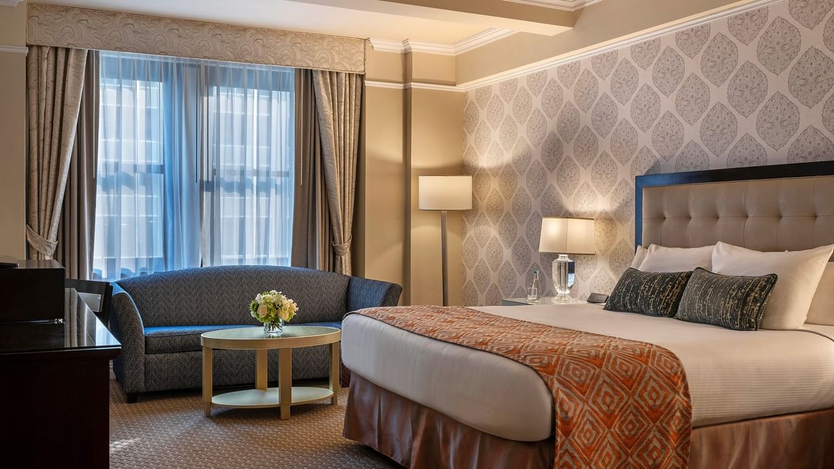 Bed with sofa near the window in the Junior Suite at Warwick New York