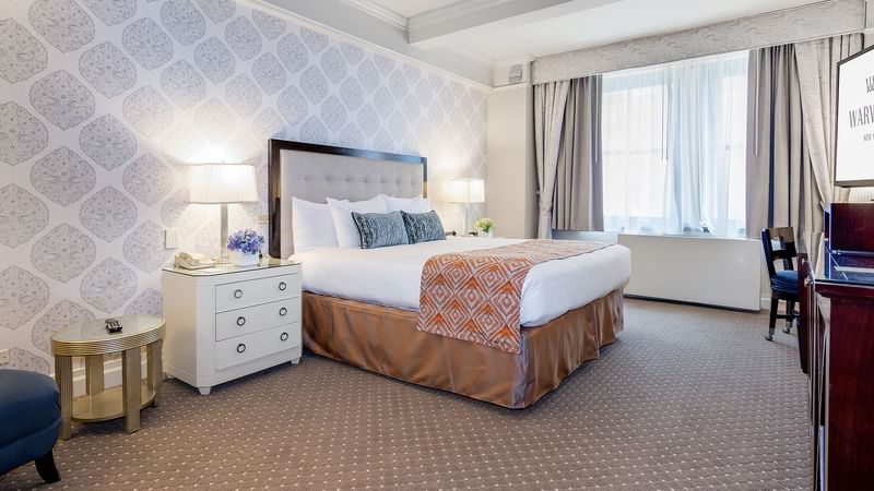 Bedside cupboards next to the bed with a cushioned headboard in the Premier City View room at Warwick New York