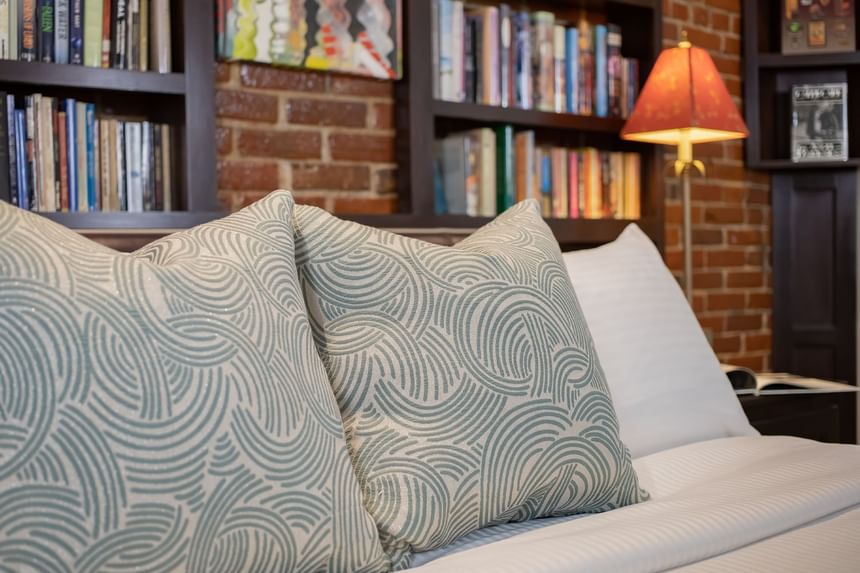 king bed with book collection in behind and an orange bedside la