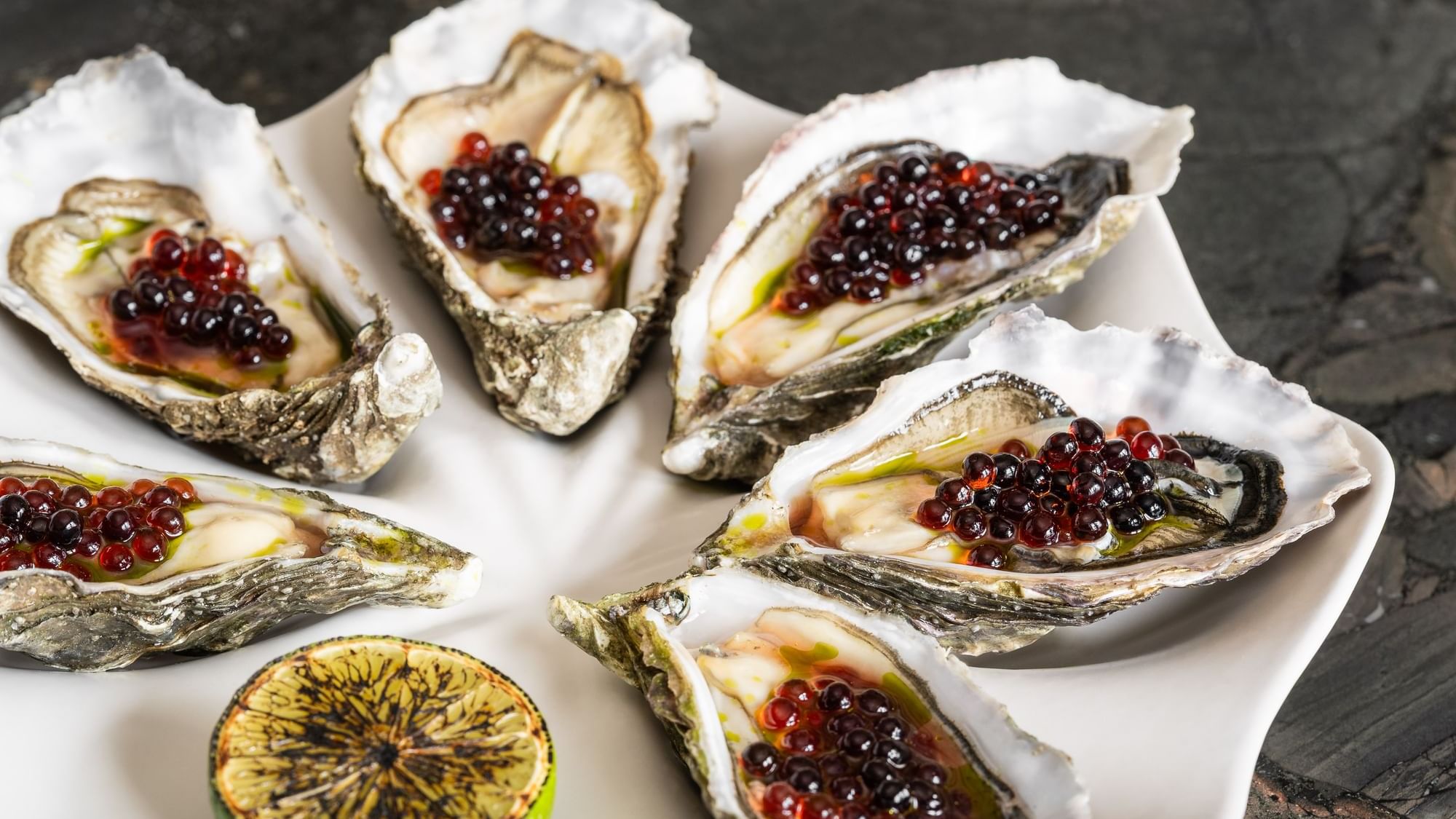 Close-up of a plate of fresh oysters topped with dark red caviar and a slice of lime served at Dunluce Lodge