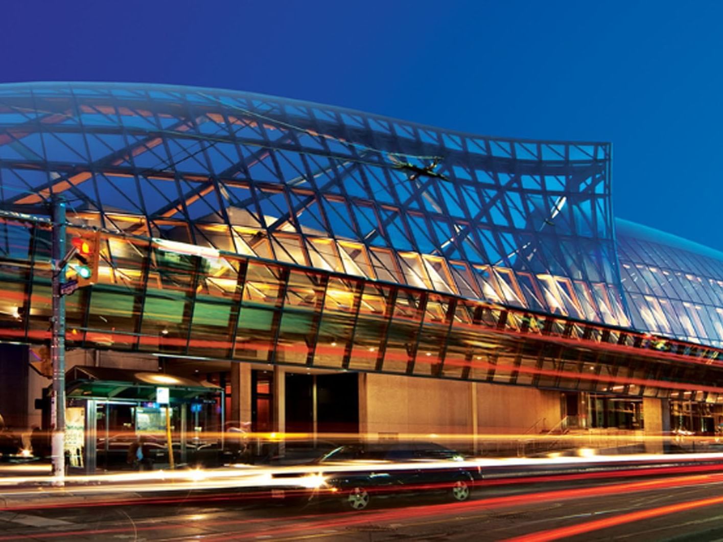Art Gallery of Ontario with geometric glass façade with light trails from passing traffic near Hotel X, a hotel in Toronto