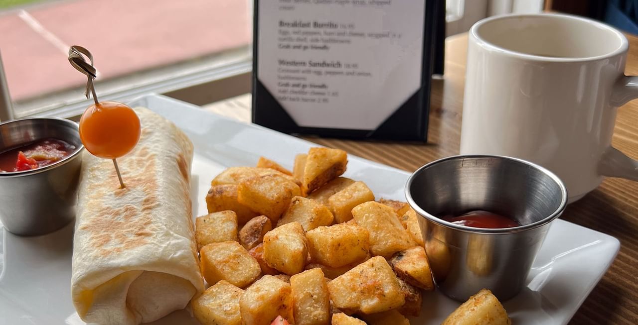 A plate of burrito, ketchup, and potatoes