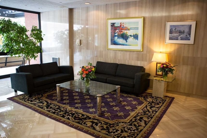 Lobby with black couch & paintings at Cartier Place Suite Hotel