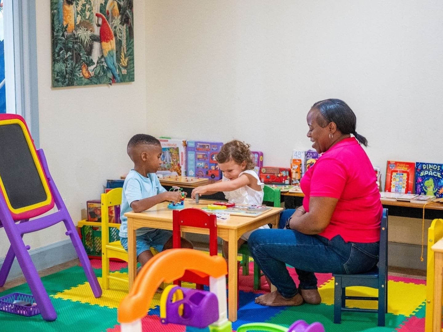 Adult and two children play at a table in Savannah Beach Hotel playroom.