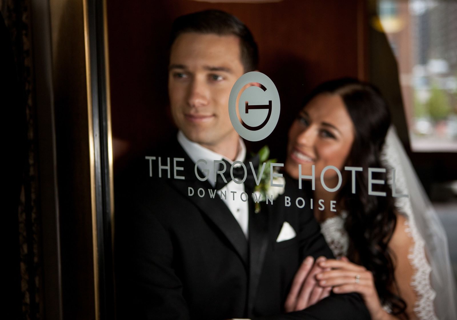 A bride and groom behind a glass door at The Grove Hotel