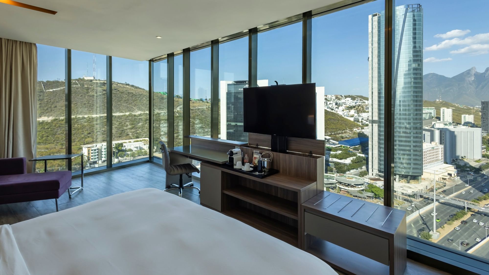 Modern junior suite with floor-to-ceiling windows showcasing mountain and city views at Camino Real Fashion Drive Monterrey