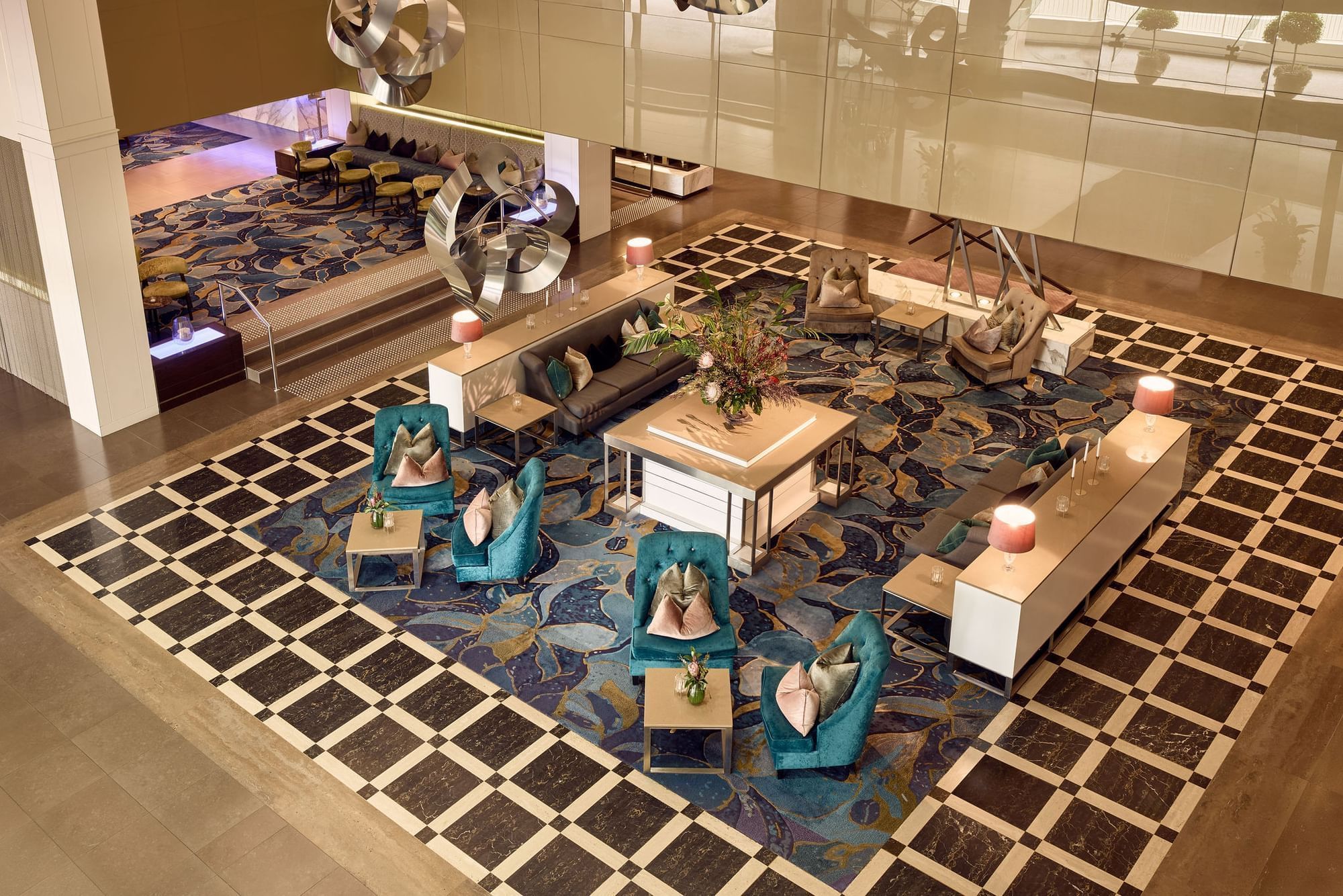 Elegant hotel lobby with teal chairs, patterned floor, and decorative lighting at Sofitel Brisbane Central