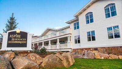 A large white building with balconies and a black sign that says Aspire Residences at The Stanley Hotel