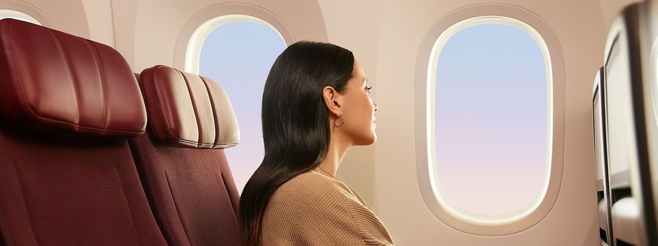 Lady gazing at the sky over the plane window featuring Pullman Sydney Olympic Park Qantas and Accor