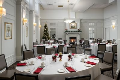Festive banquet setup with red napkins, Christmas tree & fireplace in Spencer Dining Room at Spencer Hotel