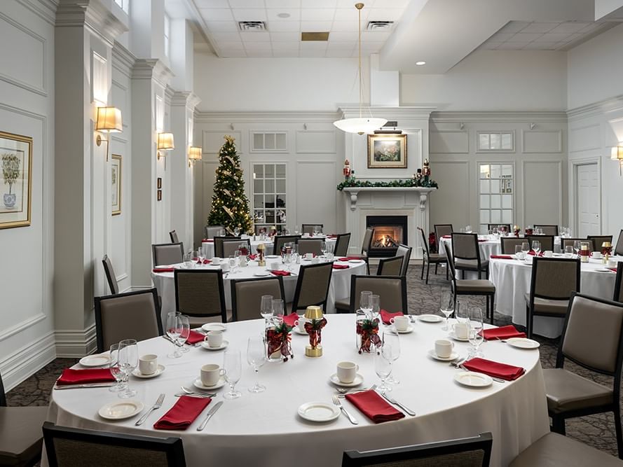 Festive banquet setup with red napkins, Christmas tree & fireplace in Spencer Dining Room at Spencer Hotel