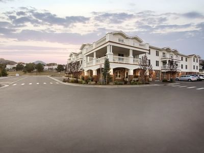 A beautiful multi-story white building with columns and balconies at The Stanley Hotel, with a wide driveway and trees