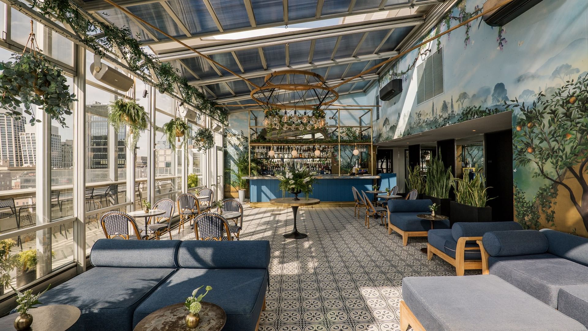 Eden at Gansevoort Rooftop features botanical murals, blue lounge seating, and a bar under a glass ceiling in New York.