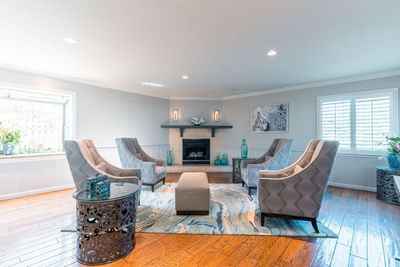 A modern hotel sitting area with four elegant gray armchairs centered around a fireplace at Carmel Bay View Inn