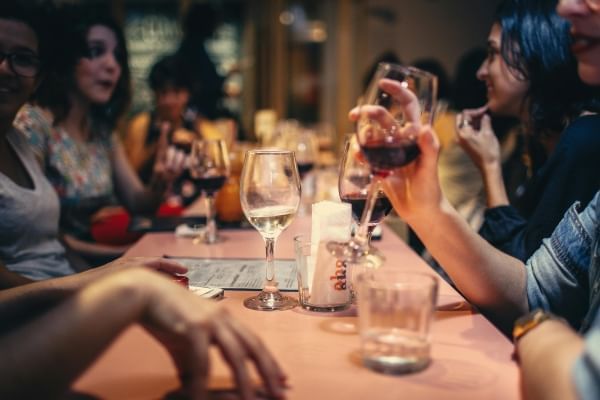 A group of people mid-conversation sitting around a long table with drinks in their hands. 