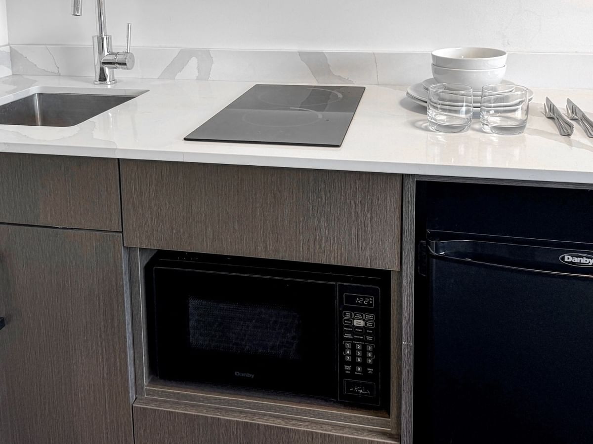 A compact kitchen with a sink, microwave, and a mini fridge.