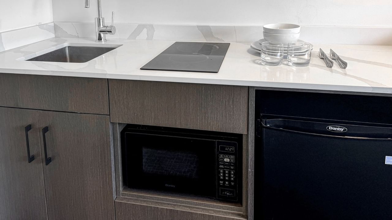 A compact kitchen with a sink, microwave, and a mini fridge.