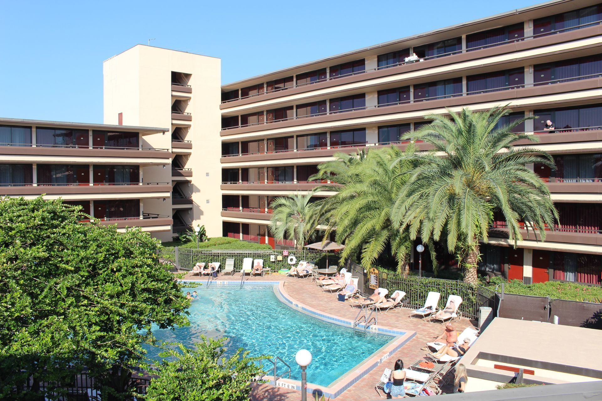 A hotel with palm trees surrounding a blue pool. 