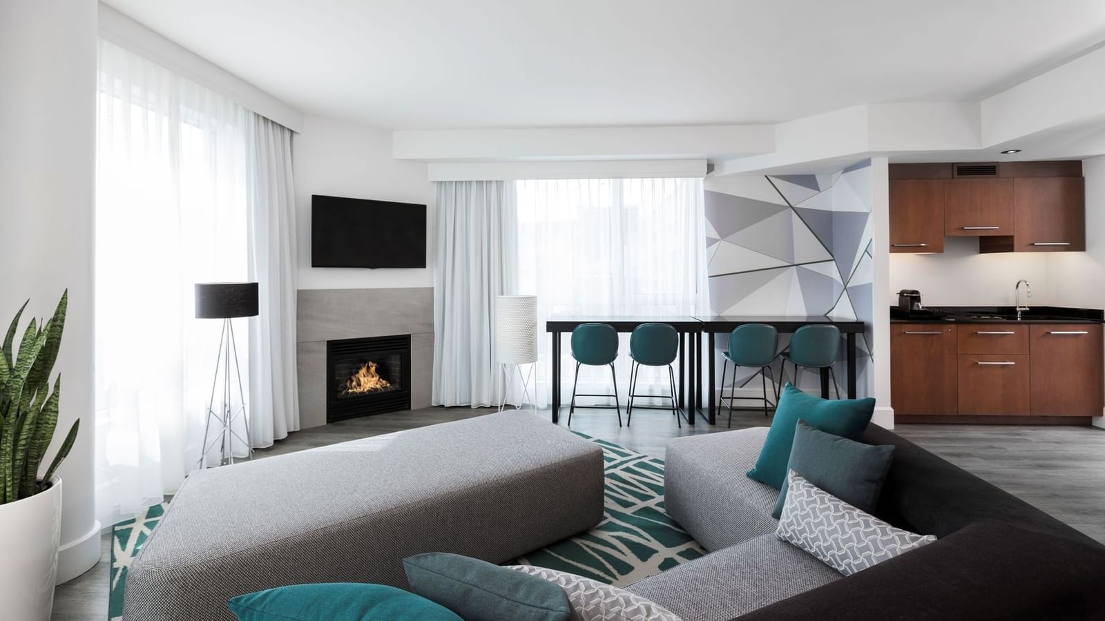 Warwick Premier Suite living area with a sofa facing the TV and fireplace at Warwick Le Crystal Montreal