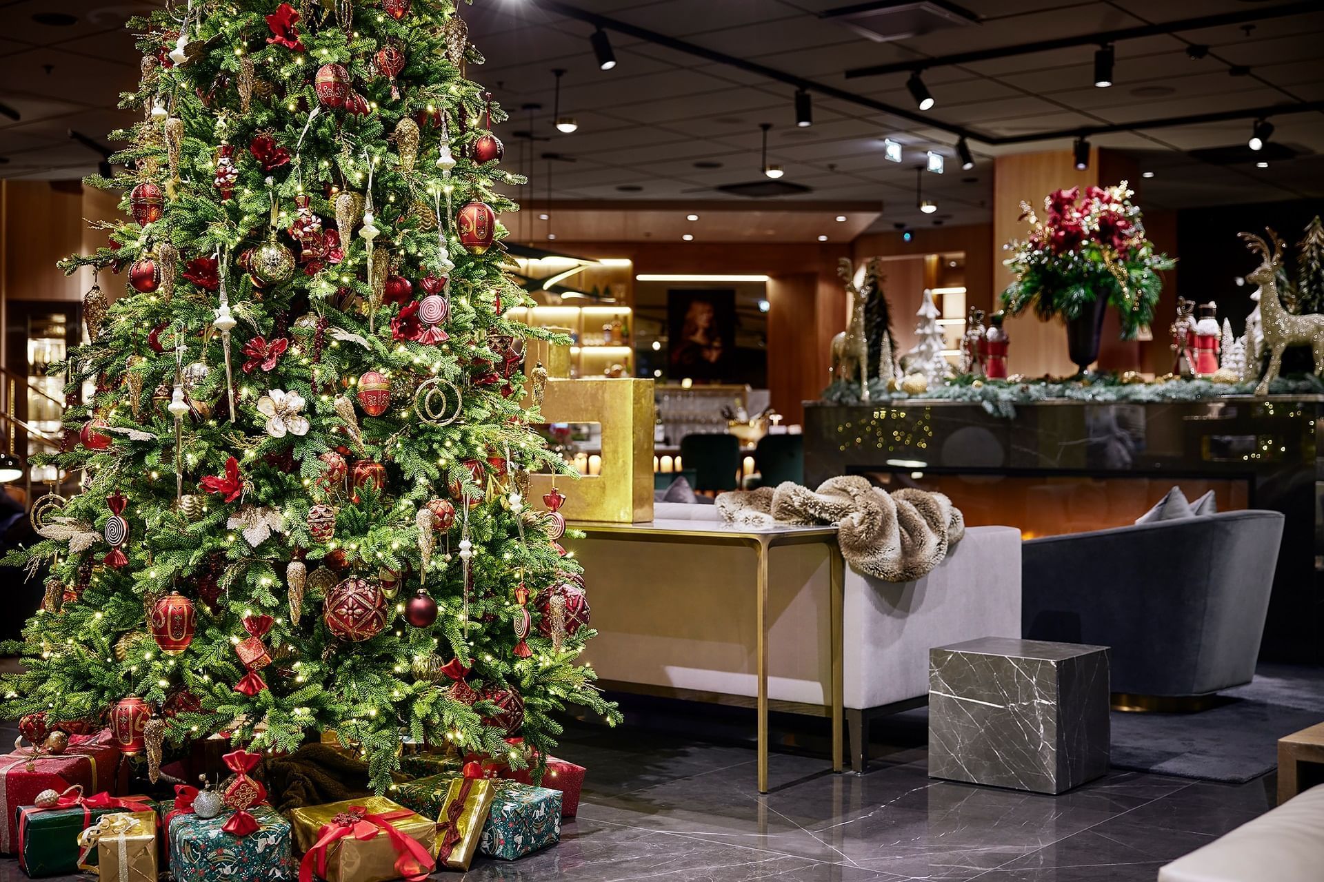Decorated Christmas tree with gifts and furniture in a modern interior with a bar counter.